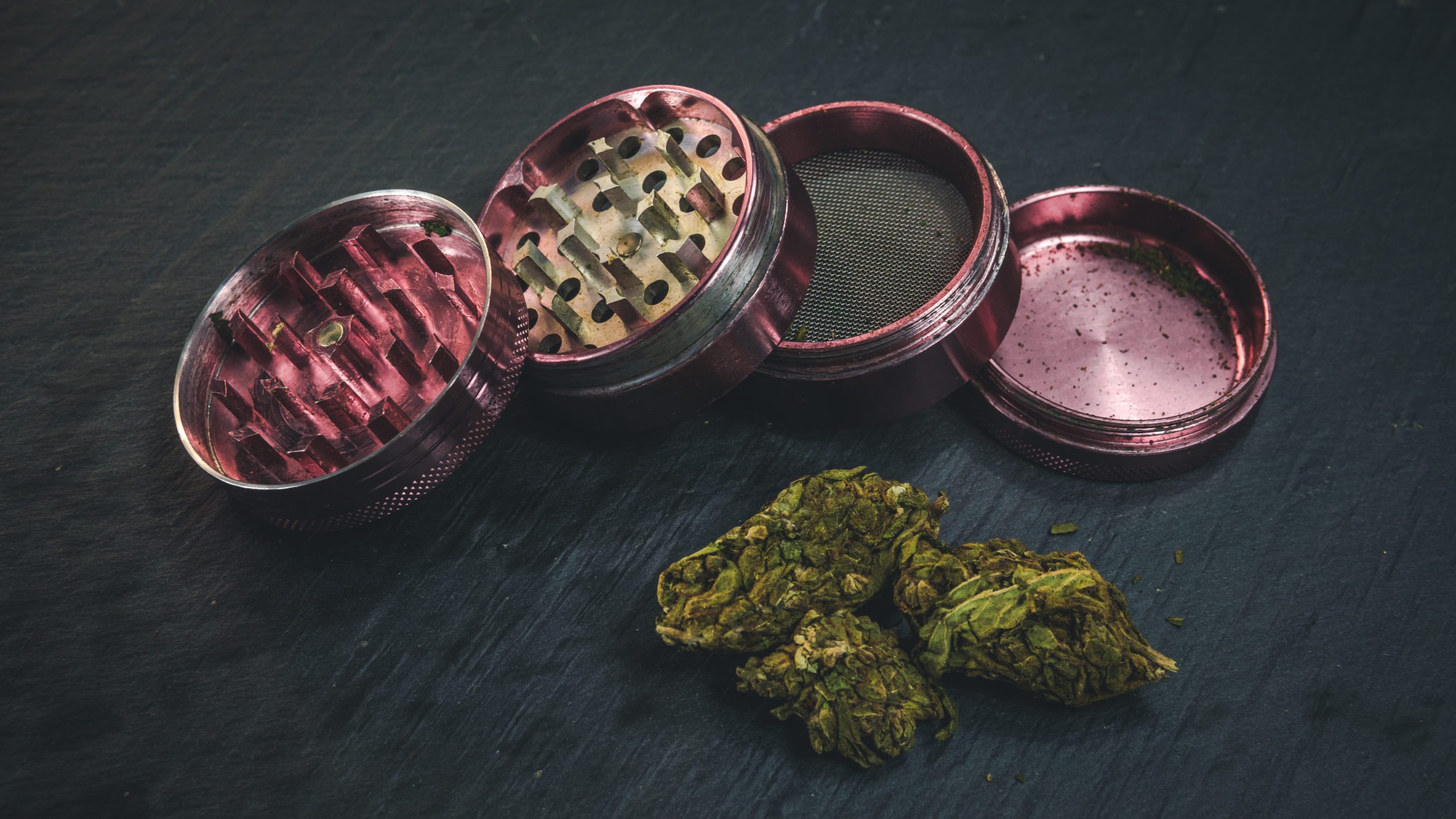 Marijuana buds and joint lie on a dark gray background. Grinder  near cannabis. Marijuana is medicine.