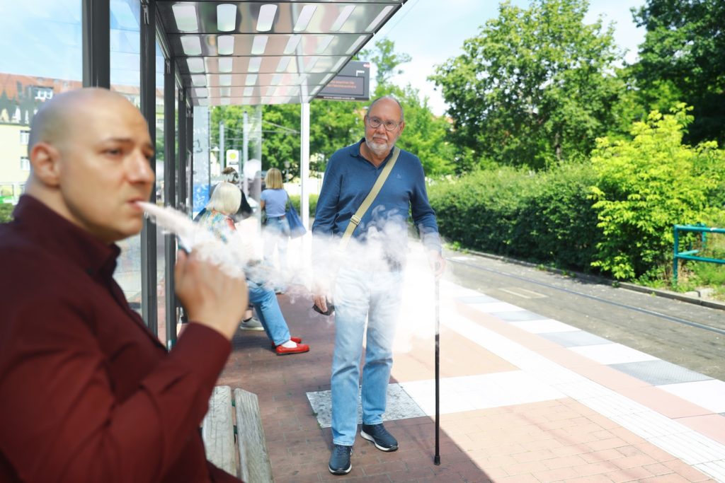 ชายคนหนึ่งสูบบุหรี่หน้าป้ายรถเมล์